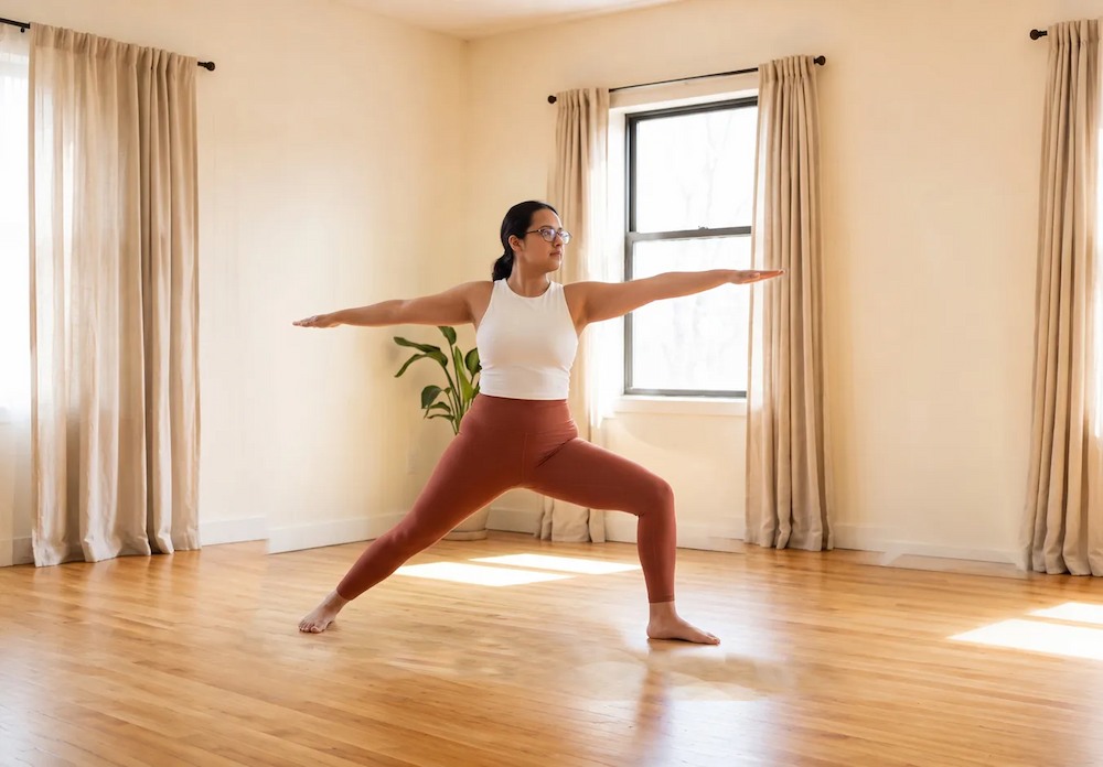 Simran practicing a standing yoga pose in a sunlit studio